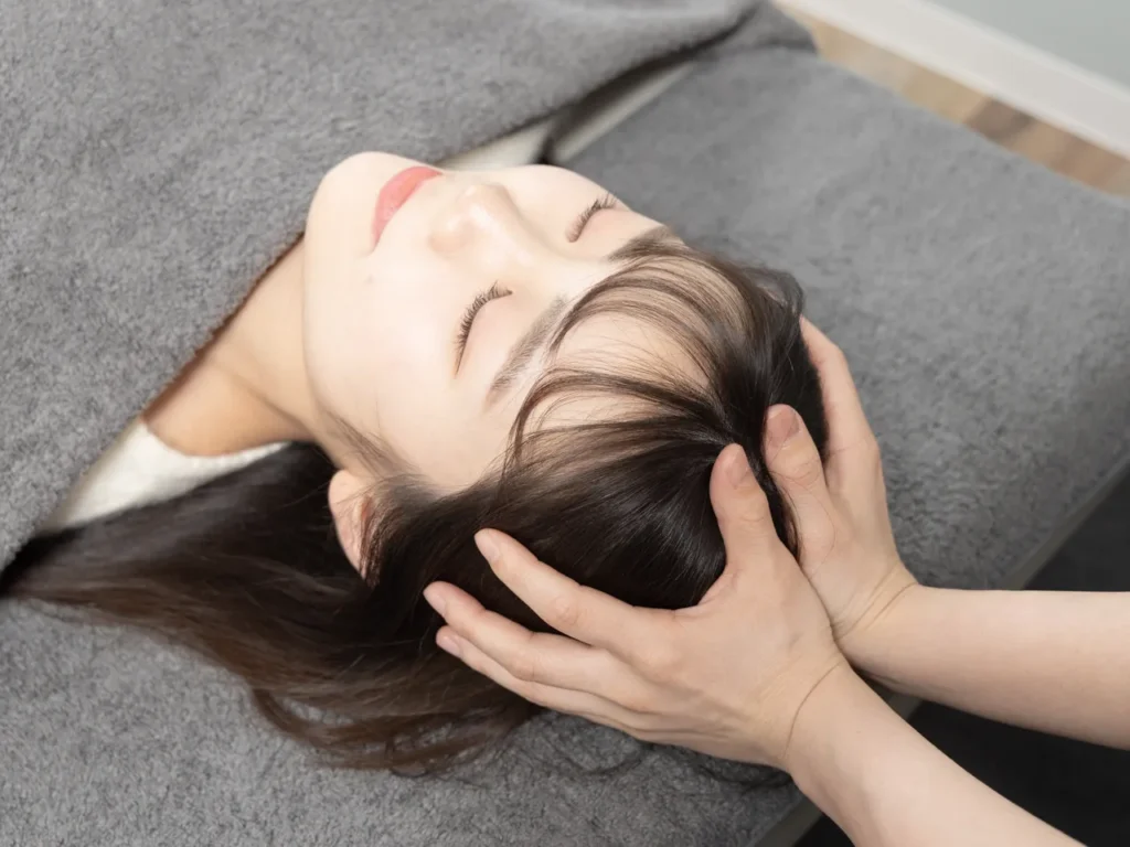 女性の頭部に両手でやさしく触れるクラニアル施術の様子。緊張をゆるめ、自律神経を整えるケア
