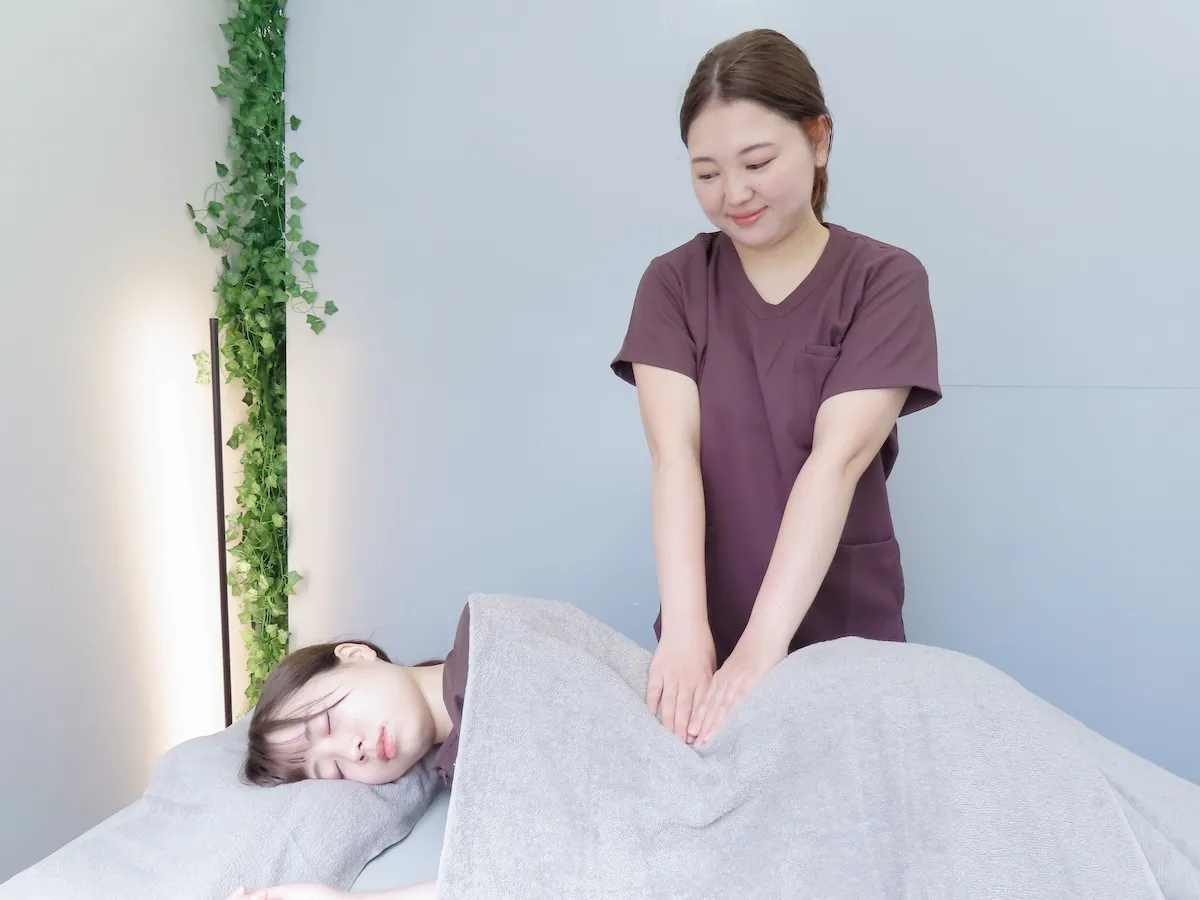 妊活整体中に内臓と骨盤のバランスを整えている施術風景。女性が横になり、施術者が丁寧にアプローチしている様子。